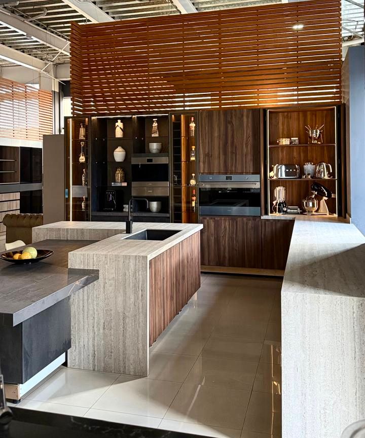 Exhibición de cocina en showroom con isla, mobiliario en madera y electrodomésticos integrados