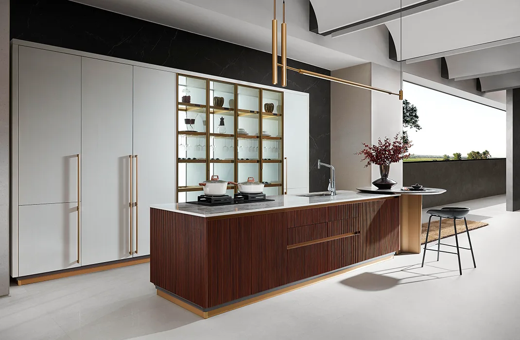 Cocina moderna con gabinetes blancos, isla de madera acanalada y vitrinas con iluminación